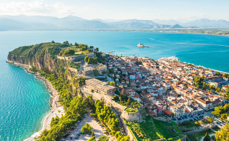 Green peninsula with Nafplion city in Greece from above with blue Mediterranean sea, old town roofs and small port