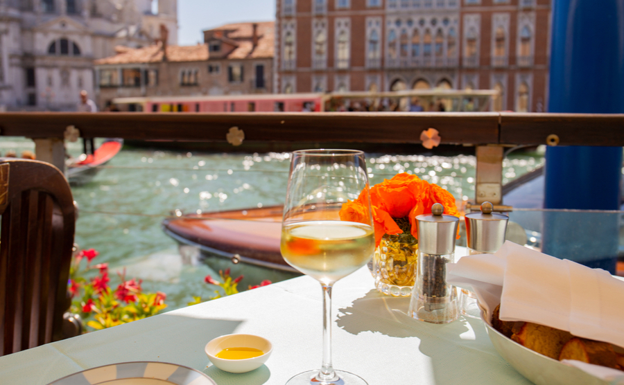 glass of wine on table in outdoor city cafe on water channel in Venice, Italy.