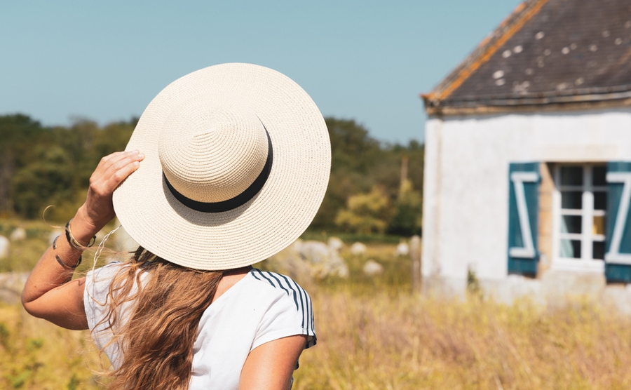 Rear view of woman with white hat and typical breton house- Brittany in France